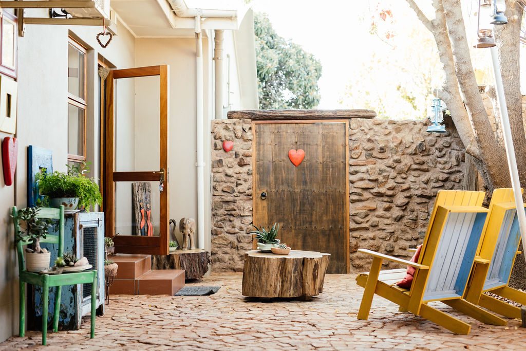 Courtyard with yellow chairs, stone wall and an open timber door