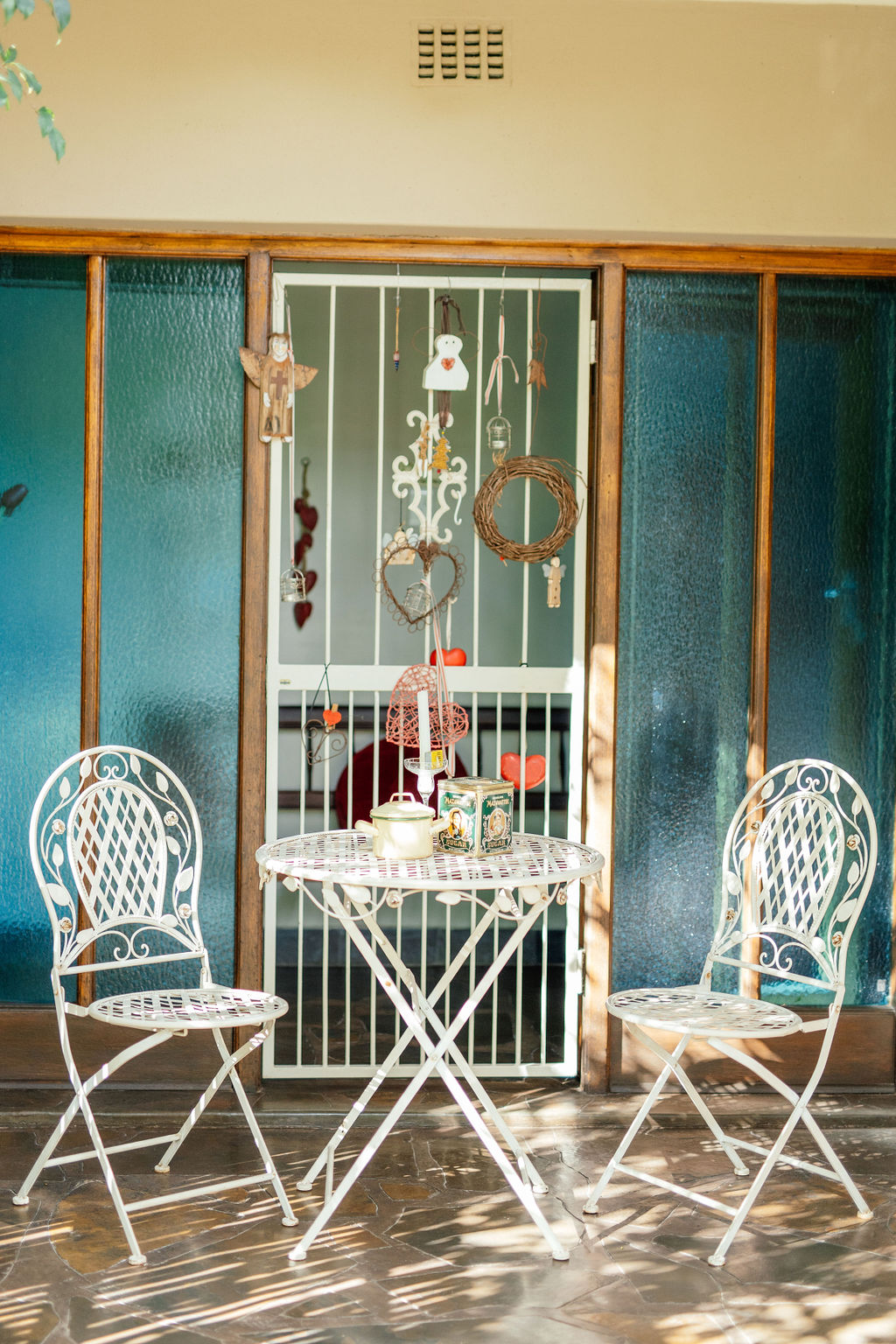 Two white metal chairs and a small table on a covered patio