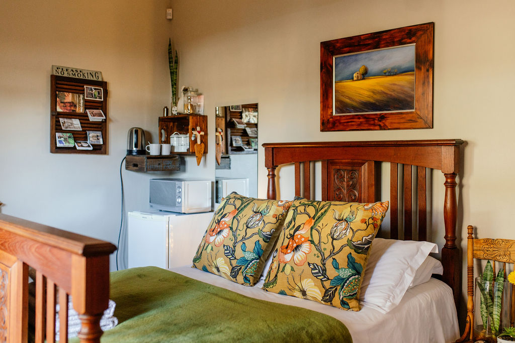 Double room with wooden bed, floral cushions and kitchenette