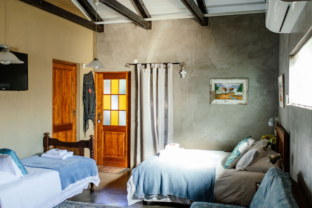 Room with two single beds, air conditioner and a timber door